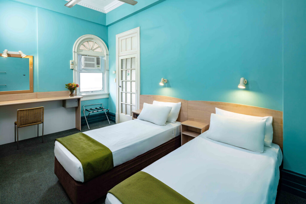 Heritage budget twin room with two single beds and an arched window at Hides Hotel Cairns